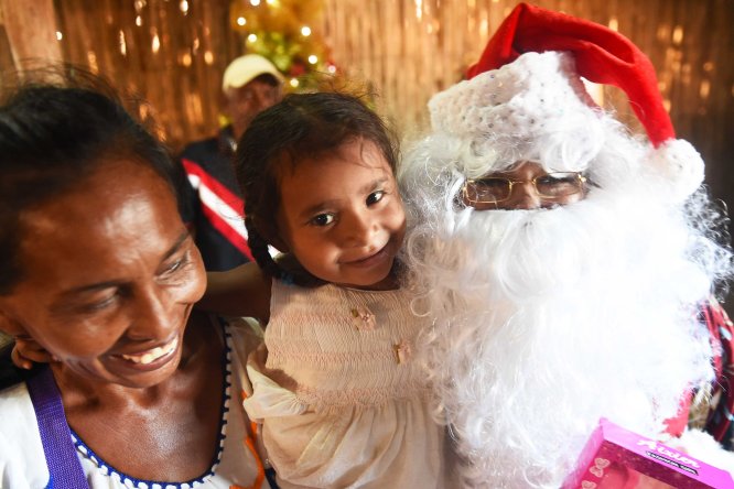 A mother a her baby from the Wayuu indigenous etnia wait receive their gift at a Christmas event where members of Kiwanis Foundation gave away gifts to Wayuu kids at the Manhaim Rancheria in Cabo de la Vela, Guajira department, Colombia, on December 23, 2017. Photo by Joaquin Sarmiento